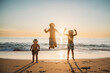 © Cavan Images - Young brothers jumping at beach having fun during summer sunset