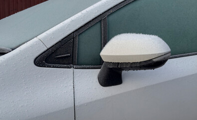 Car with frosted frost-covered windows in winter - driving safety, ice heating, preparation for the trip, side view to mirror