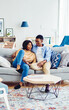 © BullRun - Carefree dark skinned marriage enjoying home recreation during weekend in cozy apartment with loft interior, African American male and female 20s hugging at comfortable couch in living room