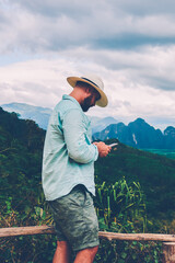 Fototapete - side view of male traveler holding mobile phone in hands and reading message via application during 
