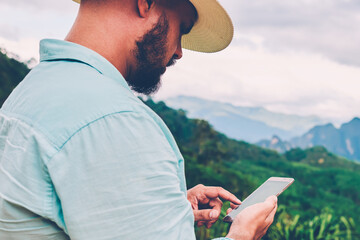Fototapete - side view of male traveler holding mobile phone in hands and reading message via application during 