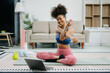 © Nuttapong punna - Woman Doing Yoga and Watching Online Tutorials on Laptop, Training in Living Room at home