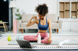 © Nuttapong punna - Woman Doing Yoga and Watching Online Tutorials on Laptop, Training in Living Room at home