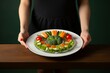 © nsit0108 - Woman presenting a balanced meal with fresh vegetables and salmon, promoting healthy eating and balanced nutrition