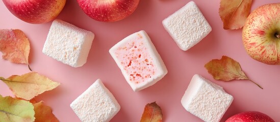 Poster - Handmade apple marshmallows arranged on a pink surface with fresh apples and autumn leaves creating a cozy seasonal vibe
