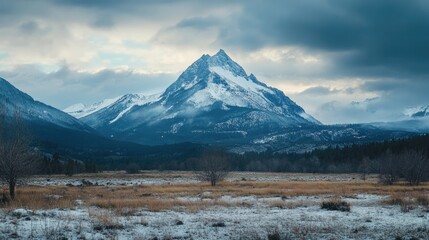 Poster - Majestic Snow-Capped Mountain Under Dramatic Clouds in Serene Landscape with Snowy Ground and Expansive Field