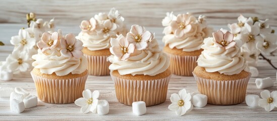 Poster - Freshly baked cupcakes decorated with creamy butter icing and delicate marshmallow flowers on a rustic wooden surface.