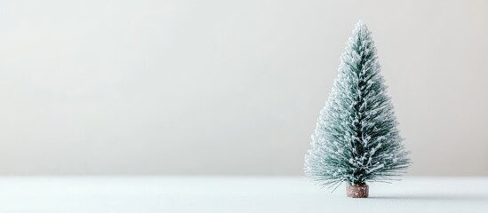 Poster - Decorative miniature Christmas tree with snow on a minimalist white background showcasing holiday spirit and seasonal charm