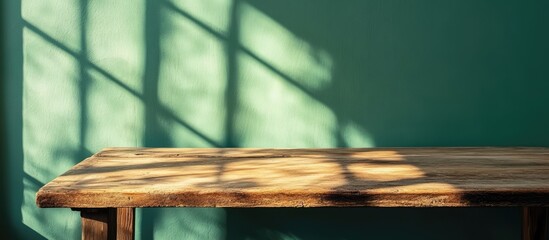 Poster - vintage wooden table casting shadows on a green wall creating a serene and minimalist interior scene