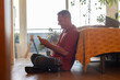 © PintoArt - Gay man relaxing at home, drinking wine and using smartphone