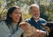© Running opossum - Young woman and a senior man are laughing while holding their dogs in a park