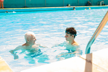 Wall Mural - Sports grandfather and grandson communicate in swimming pool