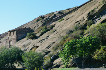 A stone structure inside a rocky mountain with trees and plants around