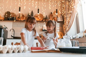 Festive interior. Two little girls are preparing food on the kitchen with garlands