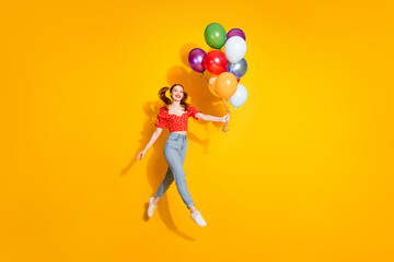 Wall Mural - Photo portrait of young red hair funky positive girl wearing blouse and jeans holding air balloons isolated on yellow color background