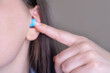 © Svetlana Golovco - Girl inserting earplugs before sleep for protection from loud noises, improving sleep quality.