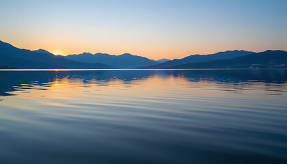 Wall Mural - Water Background: A tranquil lake with the smooth reflection of mountains in the distance creating a calming and peaceful atmosphere. background copyspace