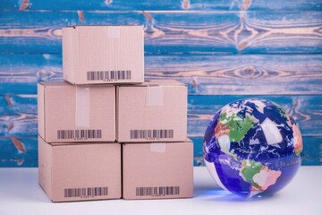 Poster - Four cardboard boxes stacked with barcodes beside a globe  symbolizing global shipping and trade.