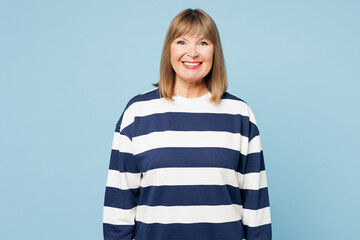 Poster - Elderly smiling happy cheerful fun blonde woman 50s years old wear striped sweatshirt casual clothes look camera isolated on plain pastel light blue cyan background studio portrait. Lifestyle concept.