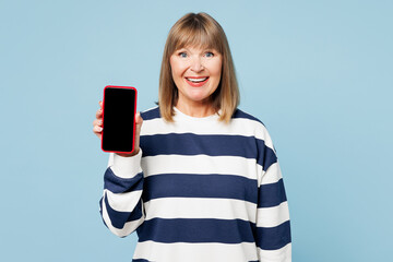 Poster - Elderly blonde woman 50s years old wear striped sweatshirt casual clothes hold in hand use blank screen mobile cell phone isolated on plain pastel light blue cyan background studio. Lifestyle concept.