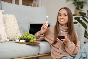 Wall Mural - Young woman with glass of wine and cheese at home