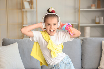 Wall Mural - Little girl in headphones listening to music at home