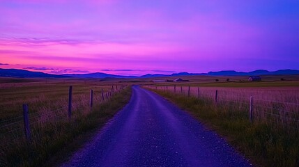 Wall Mural - Vibrant sunset over a rural dirt road, leading to distant mountains and farm buildings.