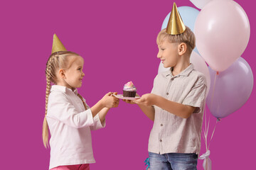 Wall Mural - Cute little happy kids in party hats with birthday cupcake and balloons on purple background