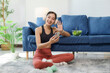 © Crystal - Smiling fitness woman wearing headphones using smartphone waving during video call at home with salad on sofa