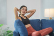 © Crystal - Fit asian woman in sportswear resting on comfortable sofa, enjoying moment of relaxation after exercising at home