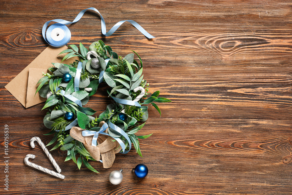 Beautiful mistletoe wreath with decorations on brown wooden background