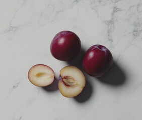 Poster - Fresh plums on a marble surface, one cut in half to reveal the inside.