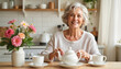 © Nataly - Smiling senior woman preparing tea in a cozy kitchen.