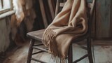 Wooden chair with cozy beige blanket draped over it in rustic setting