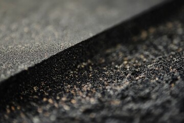 Poster - This detailed view illustrates a rough black textured material, accentuating its various surface characteristics that invite touch and interaction, perfect for design concepts.