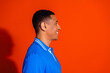© deagreez - Young man in blue polo shirt smiling against vibrant orange background