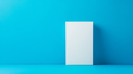 Poster - A blank white book standing upright on a blue background, ideal for branding mockups