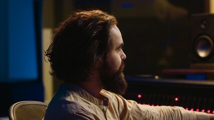 Poster - Audio expert working on recording and editing new music album, processing sounds and using mixing console in control room. Technician pushing buttons an switchers in professional studio. Camera A.