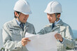 © buritora - 青空で設計図を見る作業服を着た作業員（建設・建築・設計・不動産・土木・工事・現場監督）