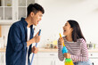 © Prostock-studio - Funny asian young man and woman in casual singing songs while house-keeping, using dust brush and mop as microphones, white kitchen interior. Domestic lifestyle, house-keeping concept