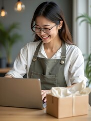 Wall Mural - Startup SME small business entrepreneur of freelance Asian woman wearing apron using laptop and box to receive and review orders online to prepare to pack sell to customers, online sme business ideas.