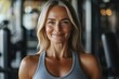 © EUT - Smiling woman in a gym, wearing a grey sports bra. Perfect for fitness, health, and wellness concepts.