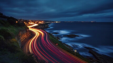 Wall Mural - Winding road with light trails along ocean shore at dusk.