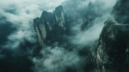 Poster - Misty mountain landscape with towering cliffs and clouds creating a dramatic atmosphere.