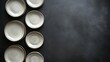 © Sirinya - Artistic top view of ceramic plates in varying sizes, symmetrically arranged on a sleek dark surface.