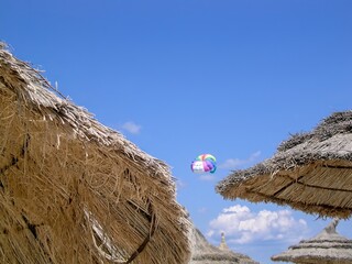 Wall Mural - A colorful parachute is flying in the sky between two umbrellas