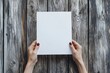 © Babycrab - Hands hold blank paper on wooden boards.