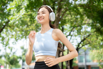 happy slim beautiful woman wearing sportswear jogging in the park with sunrise. young beautiful asia