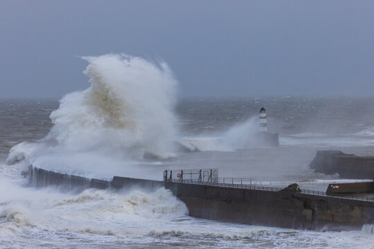 Waves crashing over the sea defence at Seaham, County Durham, England UK.