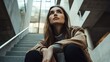 © Christopher - A female model sitting on a staircase in a modern building, looking upwards thoughtfully, relaxed pose